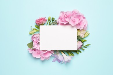 Photo of Beautiful composition with hortensia flowers and blank card on light blue background, top view. Space for text