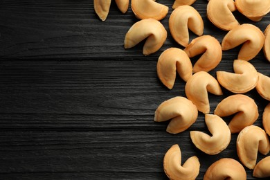 Photo of Tasty fortune cookies with predictions on black wooden table, flat lay. Space for text