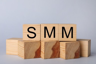 Wooden cubes with abbreviation SMM (Social media marketing) on grey background