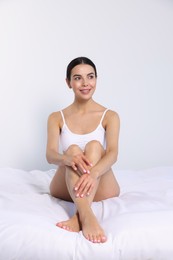 Young woman showing smooth skin after epilation on bed