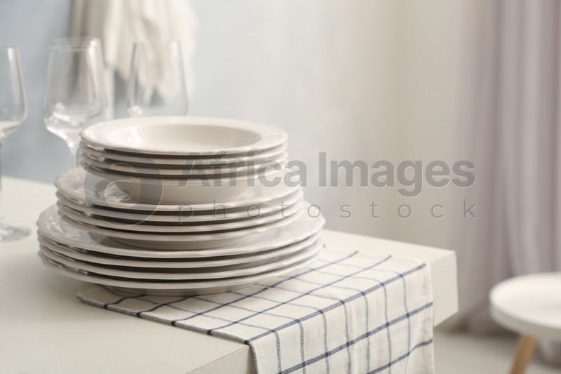 Photo of Set of clean dishware and wineglasses on white table indoors. Space for text