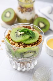 Photo of Delicious dessert with kiwi and muesli on white table, closeup