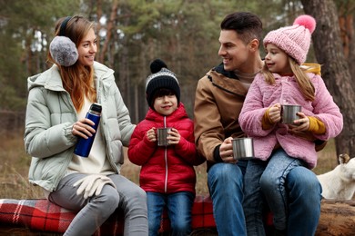 Happy family with hot drinks spending time together in forest