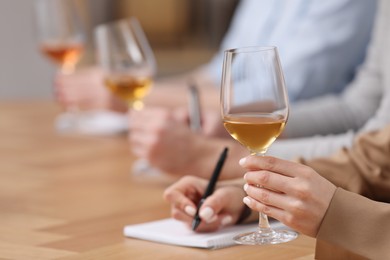 Sommeliers tasting different sorts of wine at table indoors, closeup