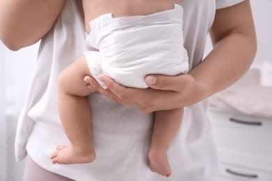 Mom holding her baby in diaper at home, closeup