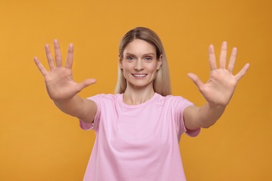 Photo of Woman giving high five with both hands on orange background