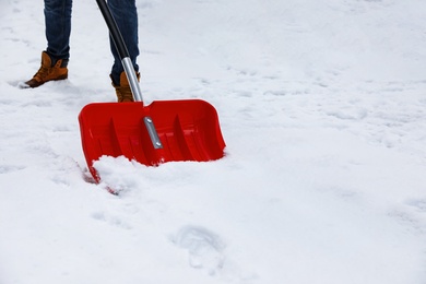 Man removing snow with shovel outdoors on winter day, closeup