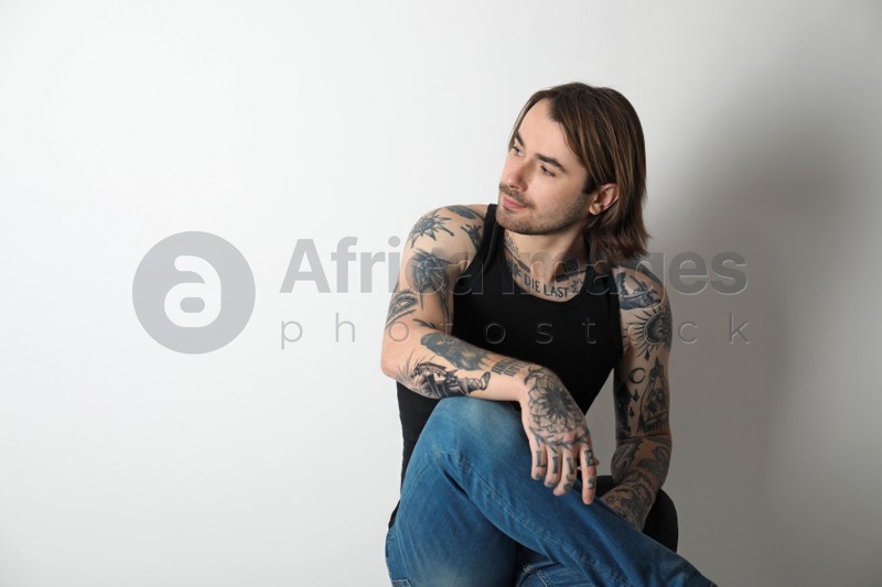 Young man with tattoos on body against white background