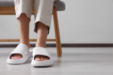 Woman wearing comfortable rubber slippers indoors, closeup. Space for text