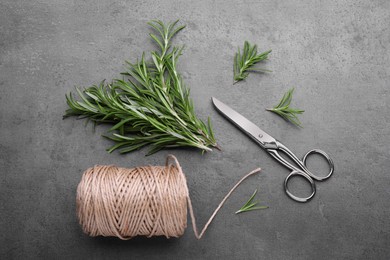 Sprigs of rosemary, scissors and twine on black background, flat lay