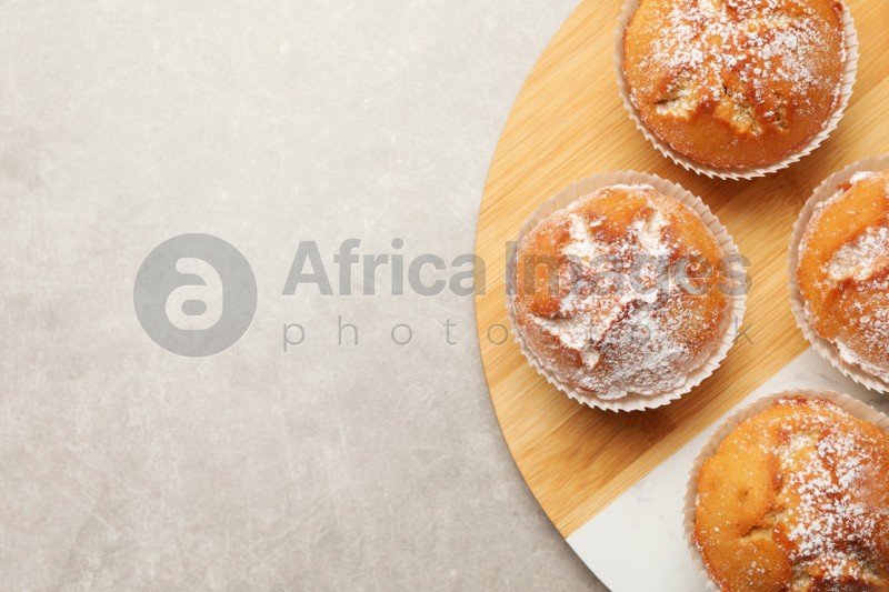 Photo of Tasty muffins on light grey table, flat lay. Space for text