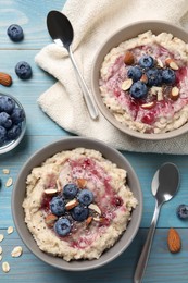 Tasty oatmeal porridge with toppings served on light blue wooden table, flat lay