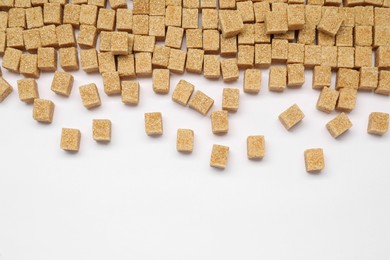 Brown sugar cubes on white background, flat lay. Space for text