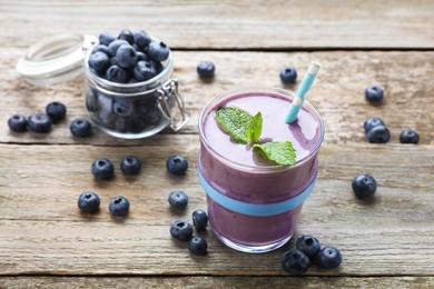 Photo of Freshly made blueberry smoothie on wooden table. Space for text