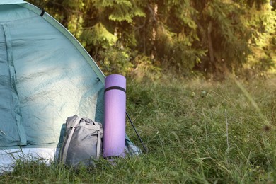 Photo of Sleeping bag and mat near camping tent outdoors, space for text