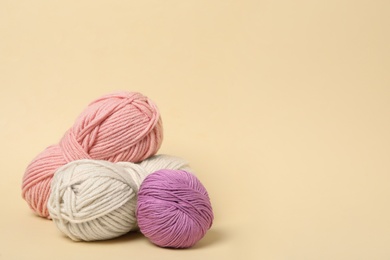 Soft woolen yarns on beige background, space for text