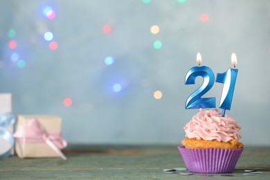21th birthday, coming of age party. Delicious cupcake with number shaped candles on light blue table, space for text