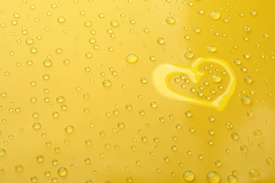 Heart shape of water and drops on yellow background