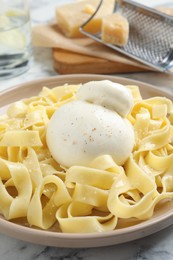 Delicious pasta with burrata cheese on white marble table, closeup
