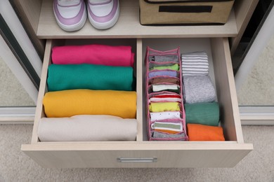 Wardrobe drawer with folded clothes and shoes, above view. Vertical storage