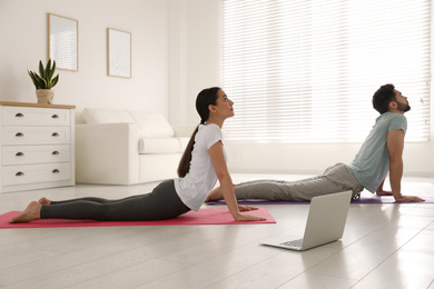 Couple practicing yoga while watching online class at home during coronavirus pandemic. Social distancing