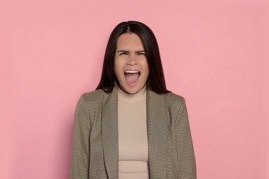Aggressive young woman shouting on pink background