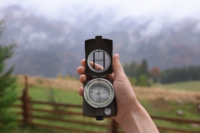 Woman using compass for navigation during journey in mountains, closeup