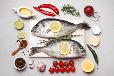 Photo of Flat lay composition with fresh raw dorado fish and ingredients on light grey table