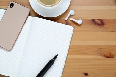 Empty notebook, coffee, smartphone and stationery on wooden table, flat lay. Space for text