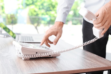 Man dialing number on telephone at workplace