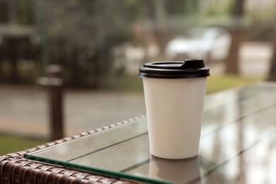 Paper takeaway cup on glass table outdoors. Coffee to go