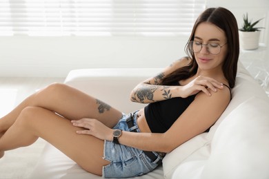 Beautiful woman with tattoos on body resting in living room