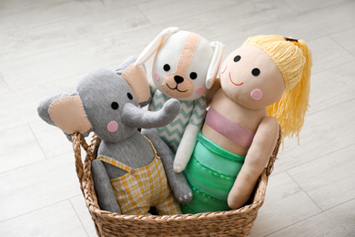 Photo of Funny toy elephant, dog and doll in basket on floor. Decor for children's room interior