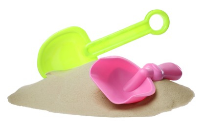 Pile of sand and colorful plastic toy shovels on white background