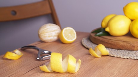 Photo of Lemon zest. Rind, fresh fruits and peeler on wooden table