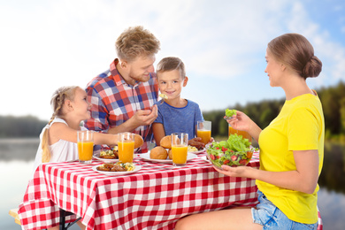 Image of Happy family having picnic at table in park
