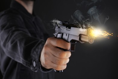 Image of Man shooting handgun on black background, closeup