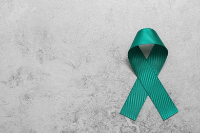 Teal awareness ribbon on grey background, top view with space for text. Symbol of social and medical issues