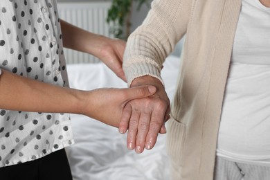 Caregiver helping elderly woman at home, closeup
