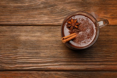 Cup of delicious hot chocolate with cinnamon stick and anise on wooden table, top view. Space for text