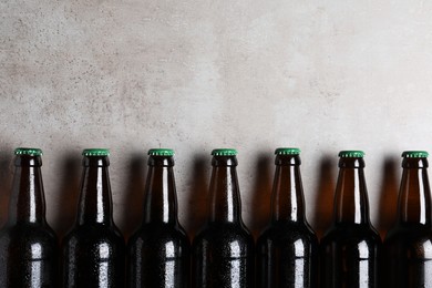 Photo of Glass bottles of beer on light grey background, flat lay. Space for text
