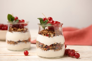 Delicious yogurt parfait with fresh red currants and mint on white wooden table