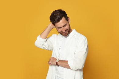 Portrait of smiling bearded man with wristwatch on orange background