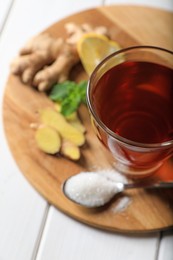 Photo of Cup of delicious ginger tea and ingredients on white wooden table, above view