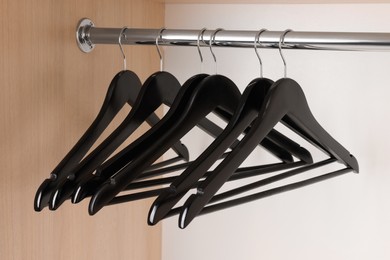 Set of black clothes hangers on wardrobe rail