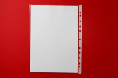 Photo of Punched pocket with paper sheet on red background, top view
