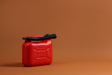 Photo of New red plastic canister on brown background. Space for text