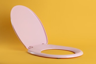 New pink plastic toilet seat on yellow background