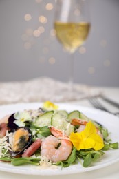 Photo of Plate of delicious salad with seafood on white table against blurred lights