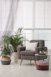 Comfortable place for rest with grey armchair near window indoors